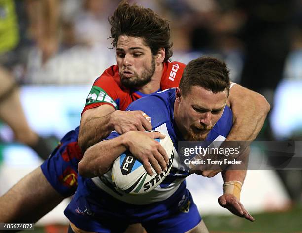 Damien Cook of the Bulldogs is tackled by Jake Mamo of the Knights during the round 25 NRL match between the Newcastle Knights and the Canterbury...