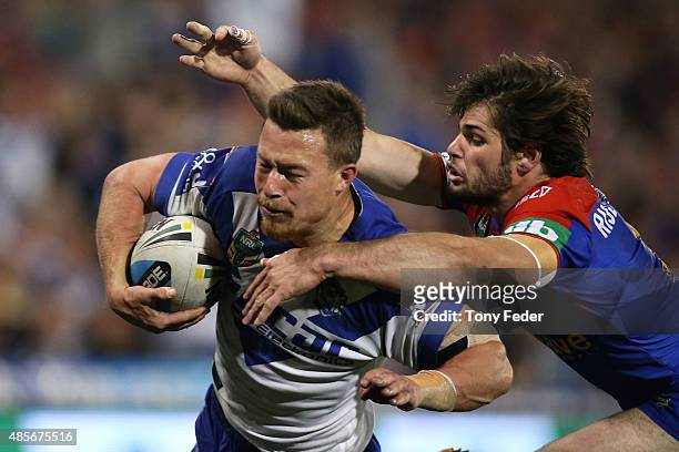 Damien Cook of the Bulldogs is tackled by Jake Mamo of the Knights during the round 25 NRL match between the Newcastle Knights and the Canterbury...