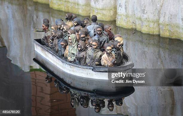 Remote controlled boat by Banksy depicts migrants at the white cliffs of Dover, as Banksy's Dismaland Bemusement Park opens to the public, on August...