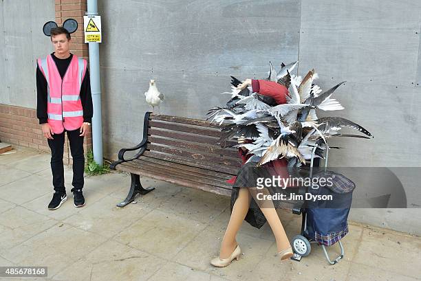 An attendant stands beside a sculpture by Banksy depicting a woman being attacked by seagulls, as Banksy's Dismaland Bemusement Park opens to the...