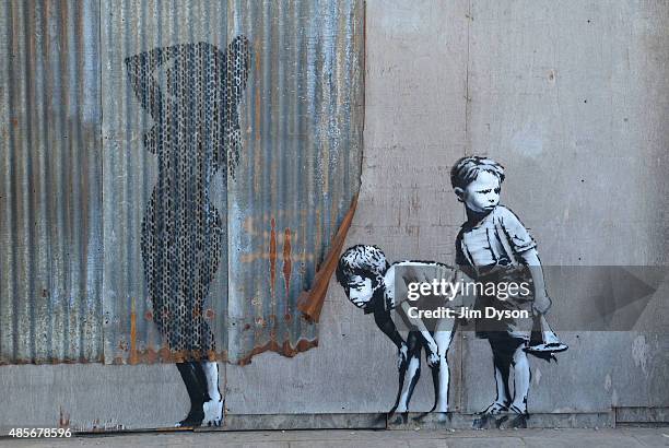 Stencil mural by Banksy depicting boys spying on a woman having a shower, as Banksy's Dismaland Bemusement Park opens to the public, on August 28,...