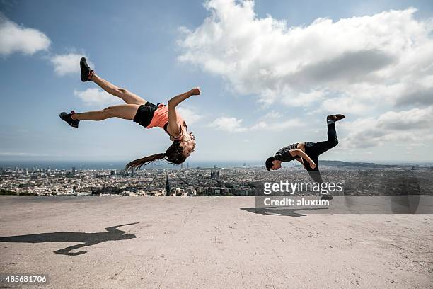 young man and woman practicing parkour in the city - achterwaartse salto stockfoto's en -beelden