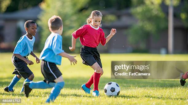 girl dribbling a soccer ball - girls football stock pictures, royalty-free photos & images