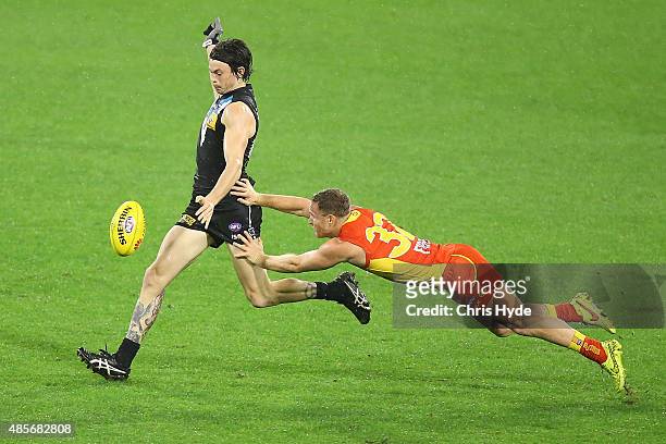 Jasper Pittard of the Power kick while tackled by Brandon Matera of the Suns during the round 22 AFL match between the Gold Coast Suns and the Port...