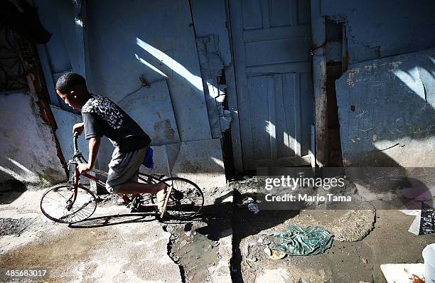 Boy rides past on a bike with no tires in an impoverished section of the occupied Complexo da Mare, one of the largest 'favela' complexes in Rio, on...