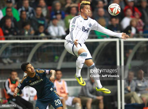 DeLaGarza of the Los Angeles Galaxy looks on as Erik Hurtado of the Vancouver Whitecaps FC leaps up for the ball during their MLS game April 19, 2014...
