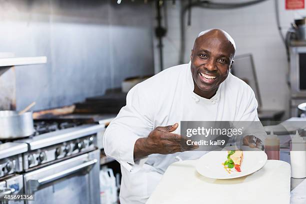 black chef in a restaurant holding dessert plate - black chef stock pictures, royalty-free photos & images