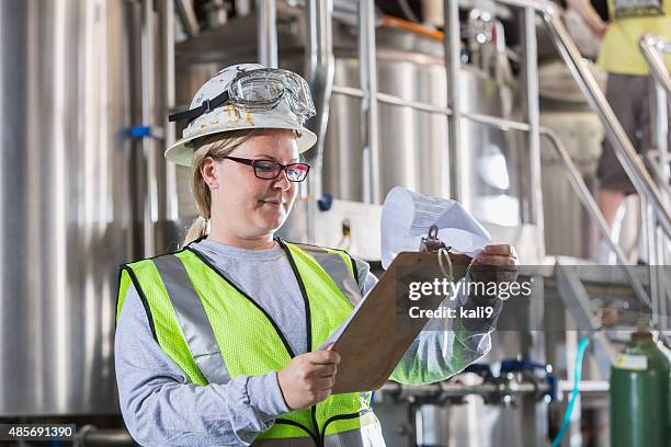 woman working in manufacturing plant with clipboard - clipboard and glasses stock pictures, royalty-free photos & images