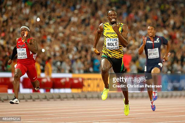 Usain Bolt of Jamaica crosses the finish line to win gold in the Men's 4x100 Metres Relay final ahead of Mike Rodgers of the United States during day...