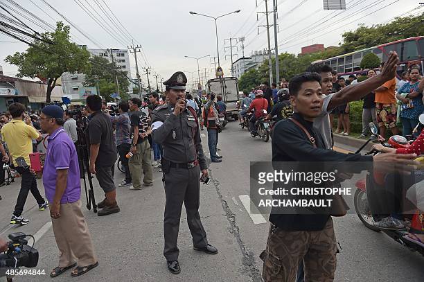 Policeman stands amid traffic outside the compound where police detained a suspect in the August 17 Bangkok shrine bombing in a Bangkok suburb on...