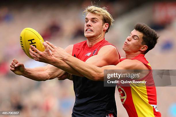 Jack Watts of the Demons handballs whilst being tackled byJaeger O'Meara of the Suns during the round five AFL match between the Melbourne Demons and...