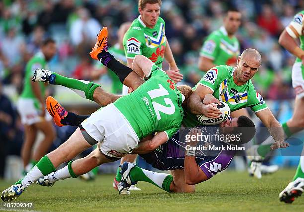 Young Tonumaipea of the Storm is tackled by Joel Edwards and Dane Tilse of the Raiders during the round seven NRL match between the Canberra Raiders...