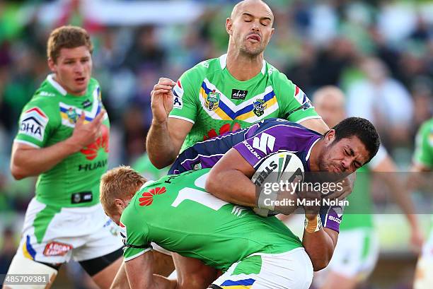 Young Tonumaipea of the Storm is tackled by Joel Edwards and Dane Tilse of the Raiders during the round seven NRL match between the Canberra Raiders...