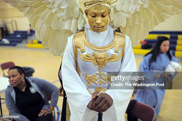Ann Redfearn, bottom left, sits near her son, Isaiah Redfearn, center, as he waits to portray an archangel during a dress rehearsal for "Who Will...