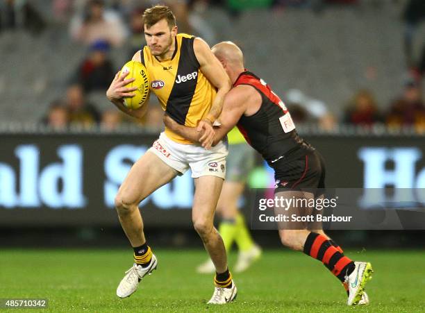 Kamdyn McIntosh of the Richmond Tigers is tackled by Paul Chapman of the Essendon Bombers during the round 22 AFL match between the Essendon Bombers...