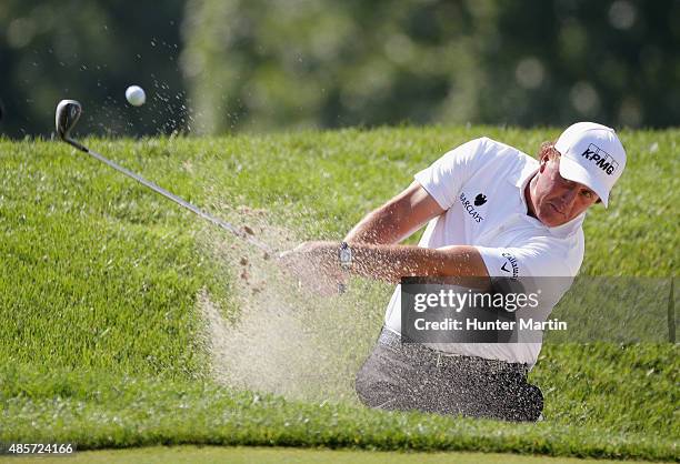 Phil Mickelson of the United States plays a bunker on the first hole during the third round of The Barclays at Plainfield Country Club on August 29,...