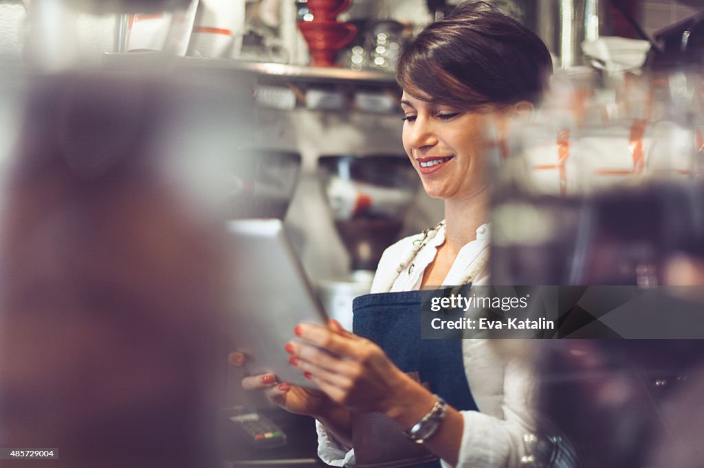 Young barista is using a digital tablet