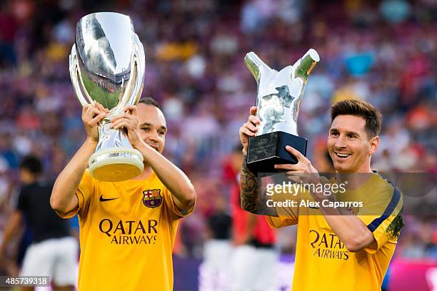 Andres Iniesta of FC Barcelona shows the UEFA Super Cup champions and his teammate Lionel Messi shows the UEFA Best Player in Europe of 2014/2015...