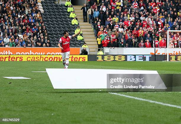 Arsenal's Spanish midfielder Santi Cazorla walks towards loose billboards after gusts of wind blew them onto the pitch, briefly stopping play in the...