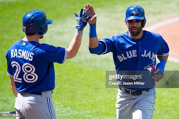 Colby Rasmus celebrates with Jose Bautista of the Toronto Blue Jays after Bautista scored on a ground out by Brett Lawrie of the Toronto Blue Jays...