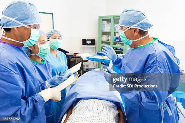 surgeon teaching hospital interns during operating on patient - now showing stock pictures, royalty-free photos & images