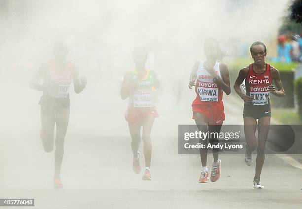 Helah Kiprop of Kenya, Eunice Jepkirui Kirwa of Bahrain and Mare Dibaba of Ethiopia enter a cooling station during the Women's Marathon final during...