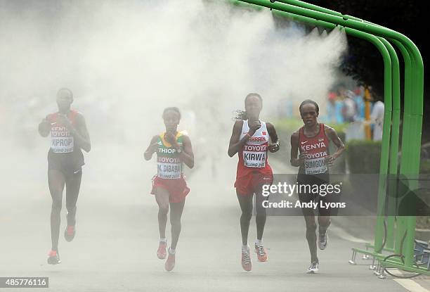 Helah Kiprop of Kenya, Eunice Jepkirui Kirwa of Bahrain and Mare Dibaba of Ethiopia enter a cooling station during the Women's Marathon final during...