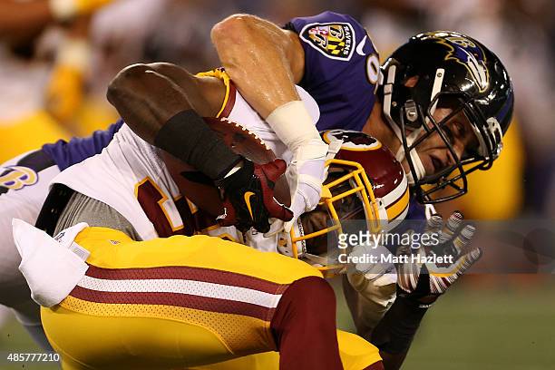 Strong safety Kyshoen Jarrett of the Washington Redskins is tackled by tight end Konrad Reuland of the Baltimore Ravens after intercepting the ball...