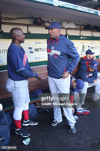 First Base Coach Sandy Alomar Jr. #15 of the Cleveland Indians talks with Nyjer Morgan in the dugout prior to the game against the Oakland Athletics...