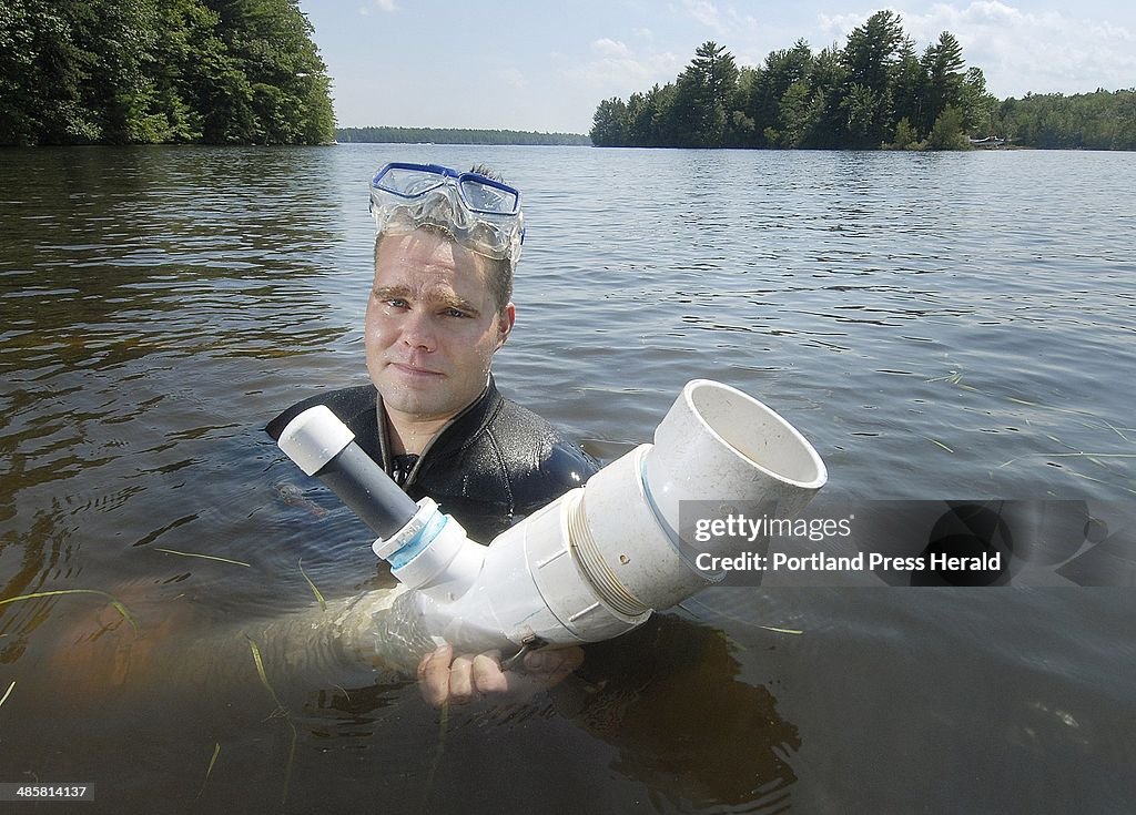 Diver Ryan Daniels holds the end of the hose that he uses to suction milfoil plants from the bottom