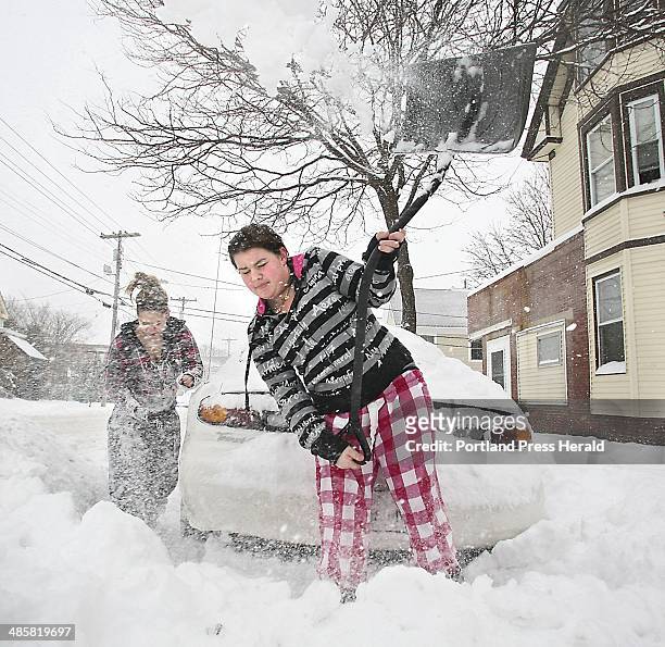 Tim Greenway/Staff Photographer -- Lexus Adams tosses a shovelful of snow as she and Ashley Hudson, also 13, dig out a car on Cumberland Avenue in...