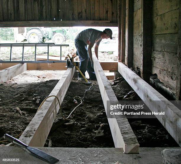 Jill Brady/Staff Photographer: -- Jon Courtney places a timber in the floor of a barn at Broadturn Farm in Scarborough on Wednesday, June 18, 2008.