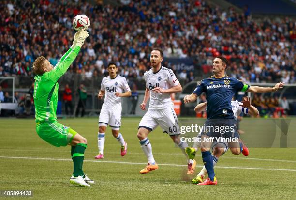 Andy O'Brien of the Vancouver Whitecaps FC and Robbie Keane of the Los Angeles Galaxy look on as David Ousted of the Vancouver Whitecaps FC makes a...