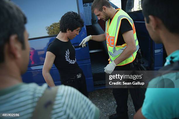 Policeman does a basic search of a group of Afghan and one Pakistani migrant shortly after they crossed from Austria into Germany on August 30, 2015...