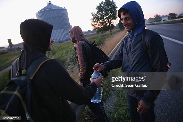 Three migrants from Afghanistan walk along the A3 highway shortly after they crossed from Austria into Germany in the early hours on August 30, 2015...