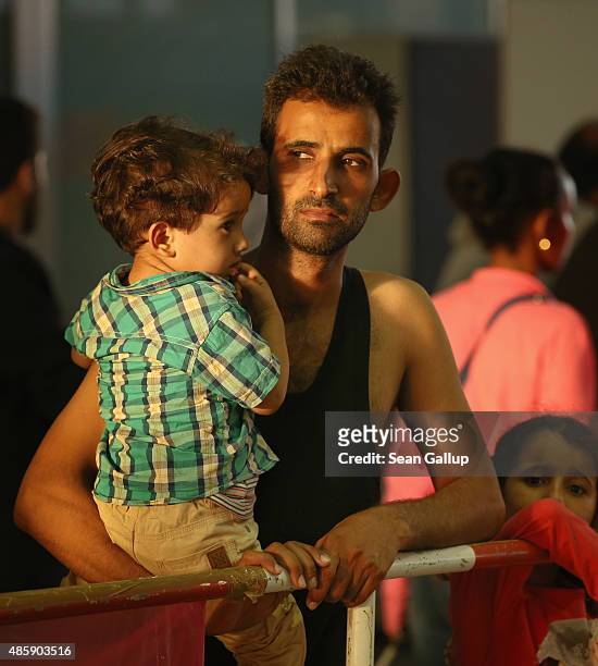 Migrant from Syria holds one of his children in a holding area after arriving at Munich Hauptbahnhof main railway station and being detained by...