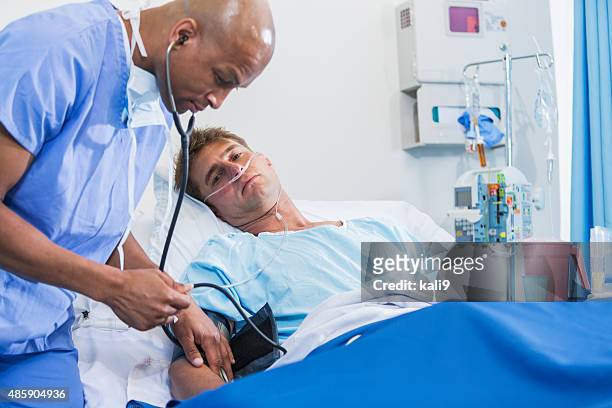 doctor or nurse with patient in hospital bed - injured man in hospital bed stockfoto's en -beelden