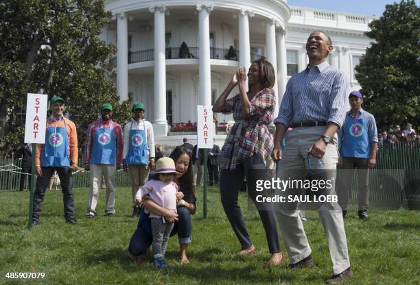 President Barack Obama and First Lady Michelle Obama react to a child rolling an Easter egg during the annual White House Easter Egg Roll on the...