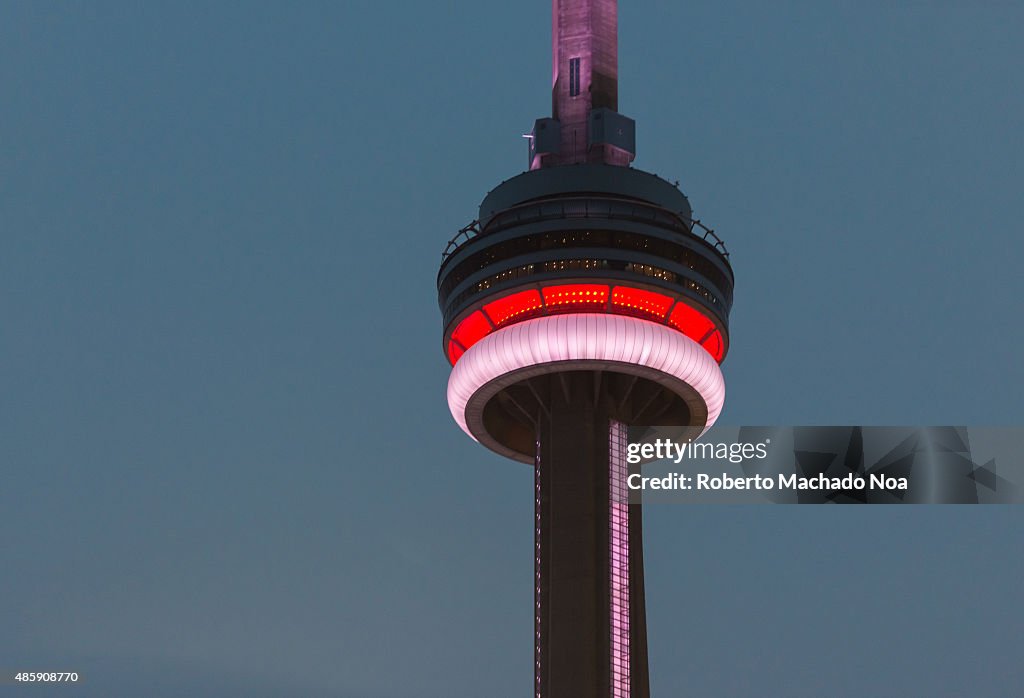 CN tower lit in pink and red light in the evening against a...