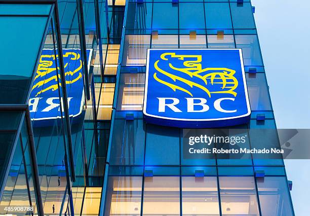 Royal Bank of Canada signage on a glass facade building. The signage has the outline of a lion holding a globe in yellow against a blue background....