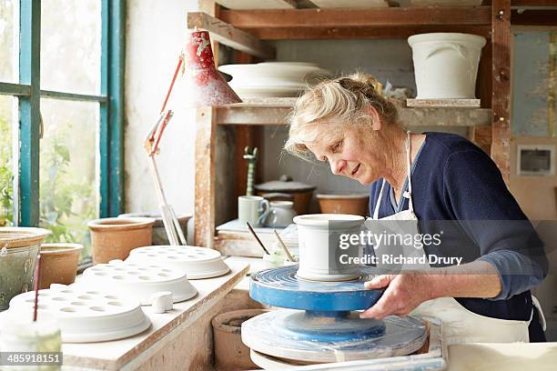 potter decorating small pot with coloured glazes - ceramic stockfoto's en -beelden