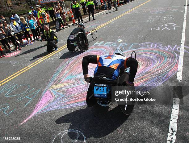 Wheelchair racers pass a giant chalk drawing of a heart on the pavement as they climb Heartbreak Hill in Newton, Mass. During the the 118th Boston...