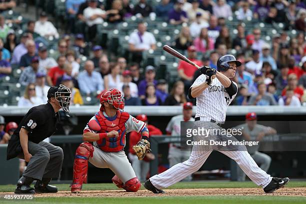 Justin Morneau of the Colorado Rockies takes an at bat as catcher Wil Nieves of the Philadelphia Phillies backs up the plate and umpire Chris Segal...