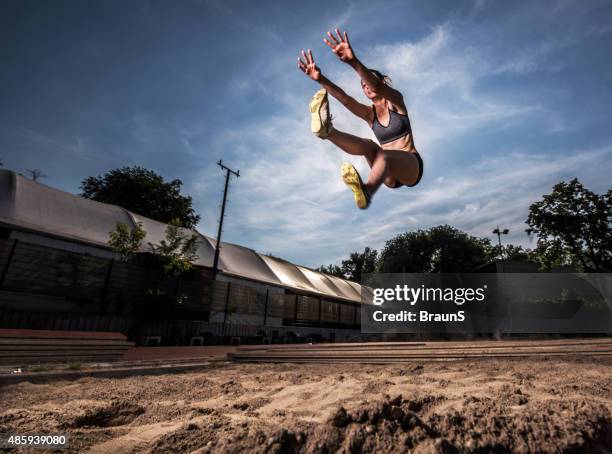 low angle view of young athletic woman in long jump. - verspringen stockfoto's en -beelden