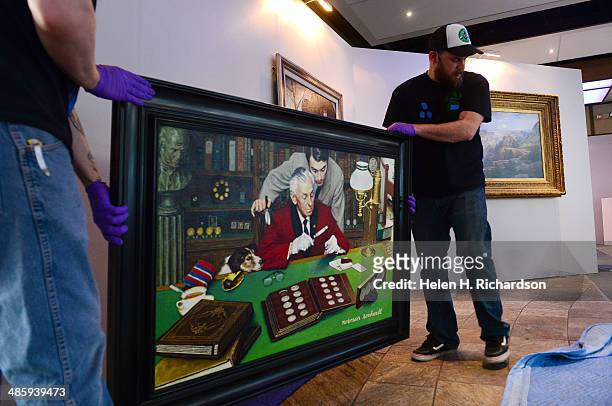 Jesse Gregory, left, and Zach Smith, right, art handlers with Ship Art, carefully lift up a painting by Norman Rockwell entitled The Collector to...