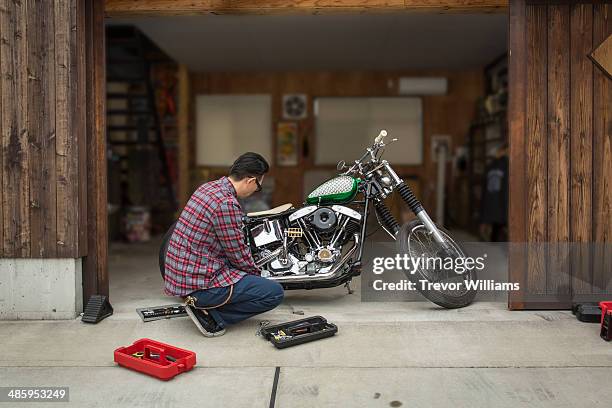 a man repairing his motorcycle in his garage - customized stock pictures, royalty-free photos & images