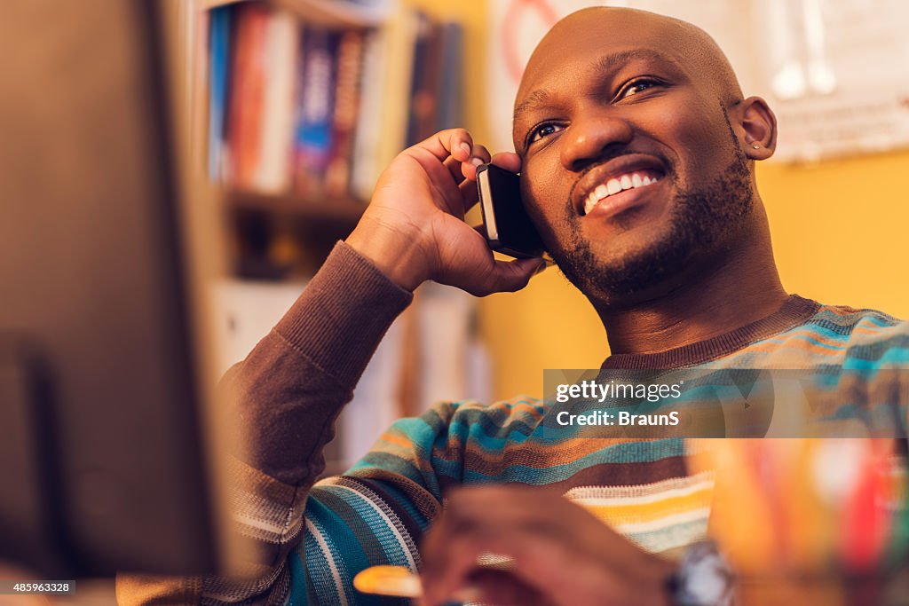 Smiling African American man talking on mobile phone.