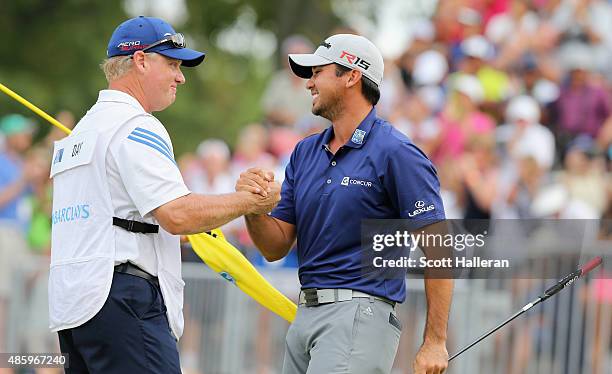 Jason Day of Australia celebrates on the 18th green with his caddie Colin Swatton after his six-stroke victory at The Barclays at Plainfield Country...