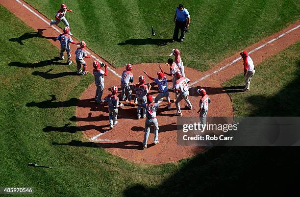 Members of team Japan celebrate while waiting for Masafuji Nishijima to cross the plate after hitting a three RBI home run against the Mid-Atlantic...