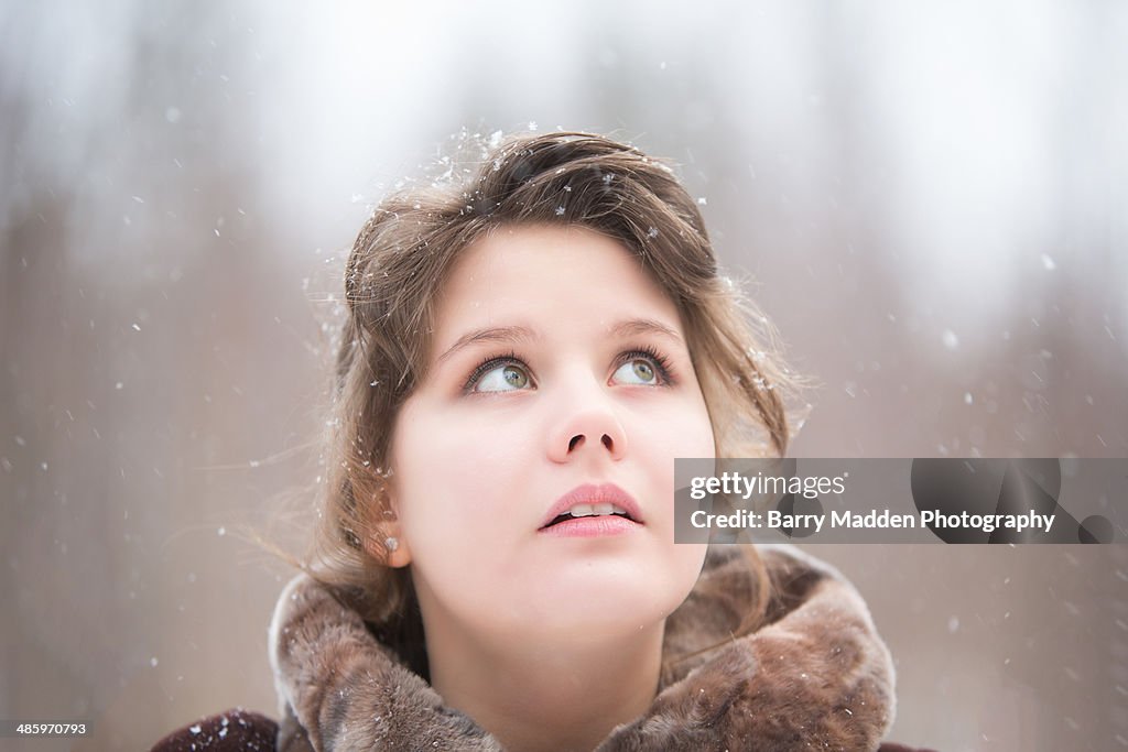Portrait of teenager looking up as it snows